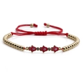 Detail of red braided string bracelet with golden Hamsa Hand charms and zircon accents - Hamsa Hand / Red Enamel