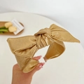 Close-up of golden faux leather bow headband with elegant pleated metallic texture - Leather Bow Headband / Gold