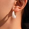 Elegant U-shaped gold earrings with white resin pendant charm on female model - F998 White Resin Gold Hoop