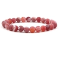 Macro detail of red frosted dragon vein agate beads on a stretch bracelet with a white background - Red