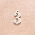 Close-up of polished silver number 3 pendant on textured pink fabric for DIY jewelry - Steel Color Number 3
