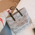 Dettaglio della borsa tote in tessuto con manici in pelle marrone e rivetti - Stile Geometrico Intrecciato Bianco e Nero (范索之河)