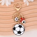 Portachiavi da calcio dorato con ciondoli bianchi e neri su superficie in legno - Stile Cuore Calcio Oro