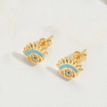 Dettaglio macro di orecchini a lobo occhio d'oro con smalto blu e zirconi bianchi lucidi - Stile Ciglia Bianche