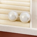 Close-up of elegant round white pearl stud earrings set in a soft beige velvet jewelry box - Silver Needle Round Faceted Style / Beige