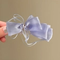 Gros plan d'une élégante pince à cheveux en dentelle violette avec un centre en cristal - Pince Torsadée / Bleu