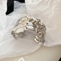 Close-up van een brede zilveren manchet met vloeibare metaalstructuur en kreukel-effect - Zilver Geplooide Stijl
