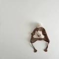 Detail of baby knit hat with faux fur pompom and cute animal pattern for winter warmth - 1-2 years old / Brown