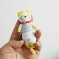Handmade crochet white cat keychain with blue and pink striped shirt and yellow accents - Light Blue Striped Cat