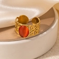 Detailed close-up of a vintage hollow gold ring with an oval orange stone on a podium - Braided Red-Orange Stone Adjustable Style (TYR0818)