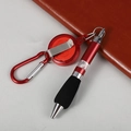 Detail view of retractable ballpoint pen with carabiner and red pen body on leather notebook - Retractable Ballpoint Pen / Red