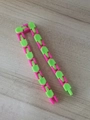 Pink and green 24-link wacky tracks fidget toy chain on a light wooden background - Green And Rose Red