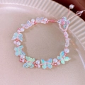 Close-up of pink butterfly pearl bracelet with adjustable woven rope on ceramic plate - Pink Crystal Butterfly Bracelet