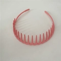 Pink flexible plastic headband with comb teeth for hair styling on white background - Pink