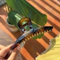 Macro shot of large tortoise shell hair claw clip with amber texture and metal spring - Shiny Tortoiseshell