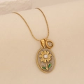 Macro shot of gold floral pendant with pearl and emerald leaves on a snake chain - Grey/White