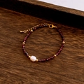 Detail of beaded necklace featuring red faceted stones, a central baroque pearl and gold accents - Bracelet / Red