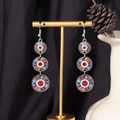 Detail of colorful bohemian three-tier drop earrings displayed on a gold stand - S4290 Red Enamel Mixed Triple Ring Earrings
