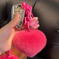 Détail d'un pendentif cœur en fourrure rose avec une chaîne en plastique et un fermoir métal - rose vif