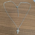 Macro shot of silver cross pendant with CZ stones shaped into a heart on wood - Silver