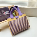 Macro shot of striped knit tote bag with purple wide strap and button detail on a ledge - Yellow Striped