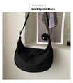 Close-up of black nylon crescent bag with adjustable strap and plush soot sprite charm - Soot Sprite Charm Style / Black