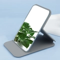 Dettaglio dello specchio cosmetico pieghevole in pelle PU grigia su elegante sfondo blu - Grigio