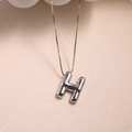 Macro shot of a 3D silver letter H pendant with a high-polished finish on a fine chain - Silver (With Necklace) H