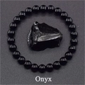 Macro shot of an 8mm black onyx beaded bracelet encircling a natural raw onyx stone - Faux Onyx