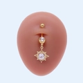 Vue détaillée d'un piercing de nombril doré avec pendentif soleil et cristaux brillants - Style Soleil Rayonnement