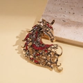 Detailed macro view of retro gold horse brooch with red rhinestones and hollow patterns - Red
