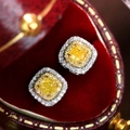 Macro shot of square yellow zircon earrings with double halo diamonds on red velvet - Yellow