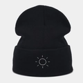 Close-up of sun embroidery detail on a black cuffed knit beanie hat for winter - Black
