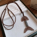 Gros plan du pendentif arête de poisson en cuir vintage et métal sur présentoir en velours - Brun Foncé