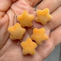 Set of five orange flocked star pendants with metal rings shown in hand for size comparison - Apricot Yellow