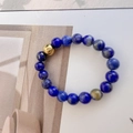 Macro detail of natural blue stone beaded ring with a polished gold stainless steel bead - Lapis Blue Round Beads Style