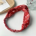 Close-up of red paisley pattern headband with twisted knot design and elastic band - Red