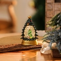 Macro shot of a Christmas tree snow globe on a wood bark stand with festive glitter - Green Christmas Tree