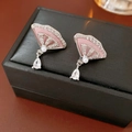 Gros plan de boucles d'oreilles en nacre rose avec goutte de zircon sur un coffret à bijoux noir - Pendentif en Forme d'Éventail Goutte d'Eau / Argent Rose