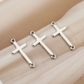 Macro shot of three polished silver cross pendants with dual loops on champagne fabric - Silver