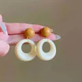 Détail de boucles d'oreilles fleurs asymétriques avec perles en résine jaune pour l'été - Clous d'oreilles rétro color-block perle jaune et anneau blanc