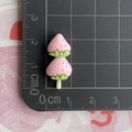 Detail view of pink strawberry resin charm with green leaves on a black measurement mat - Strawberry Strings / Light Pink