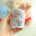 Pink metal tin canister featuring a cute rabbit wedding illustration, held by hand - Bunny Couple