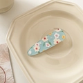 Detail view of light blue acrylic flower hair clip on a beige octagon tray - Light Blue White Floral