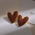 Detail of vintage heart earrings with brown enamel texture on a white marble display - Coffee