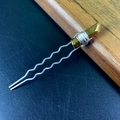 Dettaglio di una forcina in argento a forma di U con accento dorato su legno scuro - Oro
