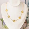 Golden necklace with five sunburst texture flower pendants displayed on jewelry bust - Necklace