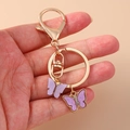 Porte-clés doré avec pendentifs papillon en strass violets sur un fermoir mousqueton - Violet
