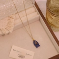 Dettaglio della collana con ciondolo a pesce in pietra naturale e zircone su portagioie - Lapislazzuli
