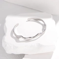 Eleganter silberner Edelstahl-Armreif mit Wellendesign auf minimalistischem Stein - Silber